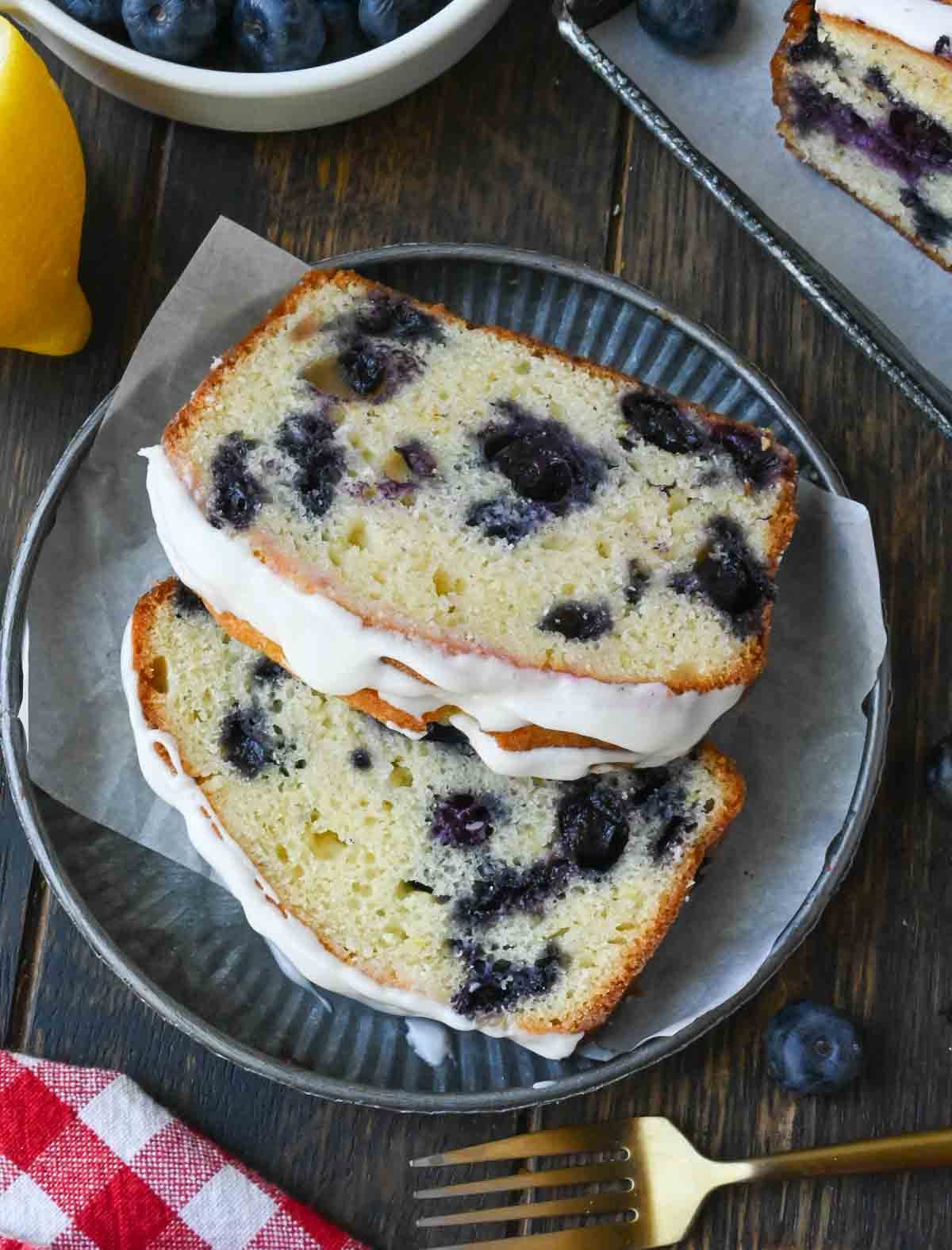 Two slices of lemon blueberry bread on a plate with a fork.