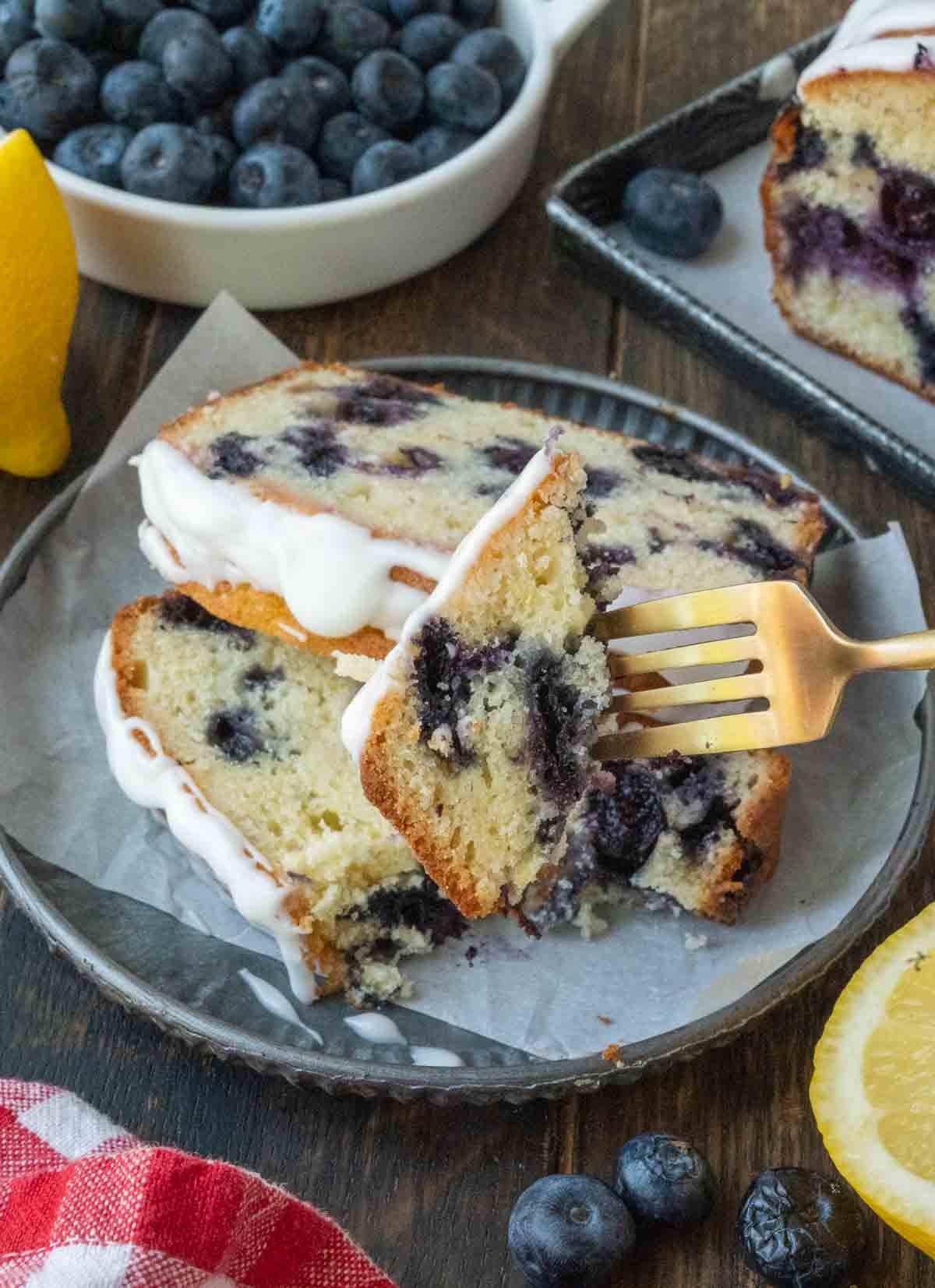 A fork taking a bite of the lemon blueberry bread.