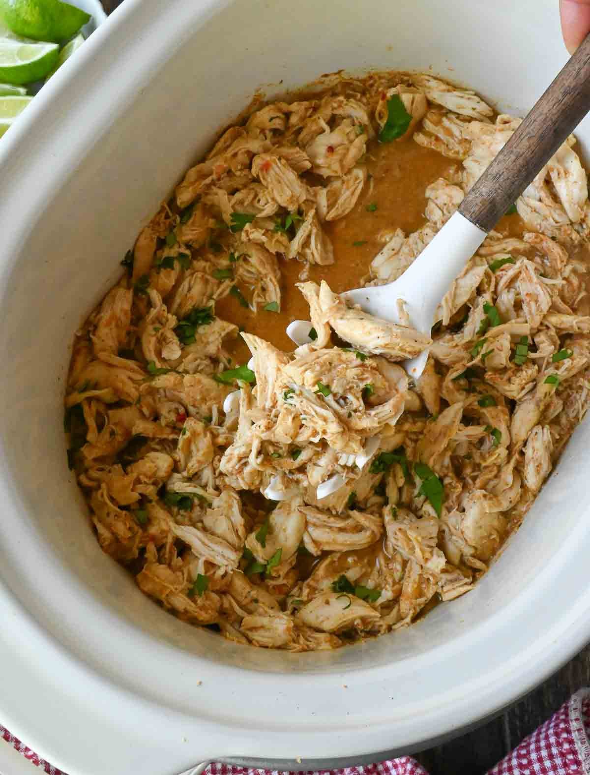 Scooping up chicken from a slow cooker.