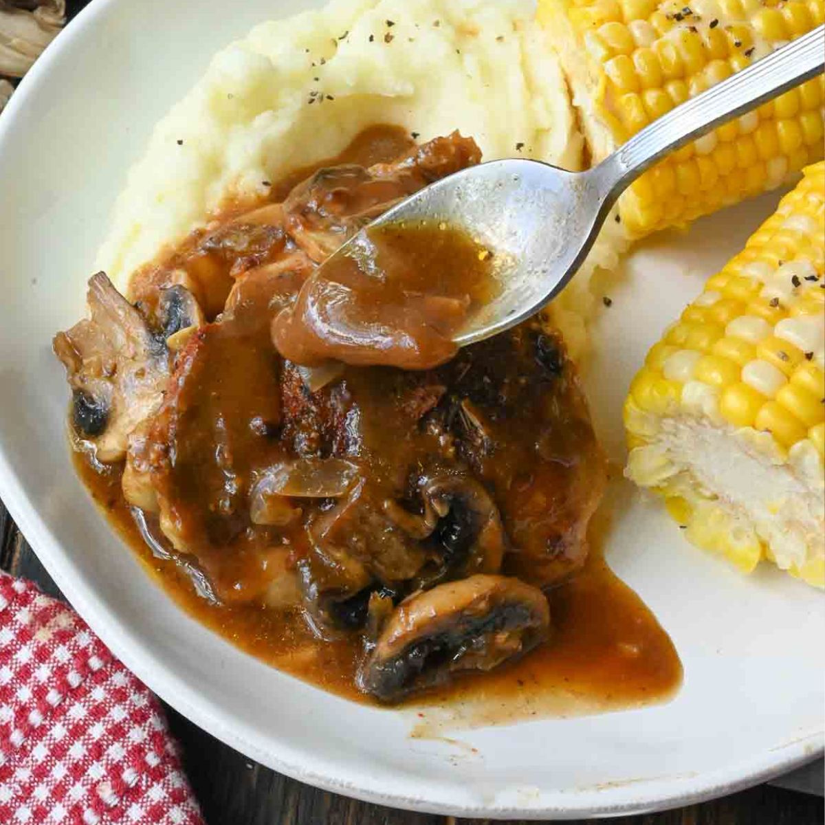 Spooning gravy over slow cooker smothered chicken.