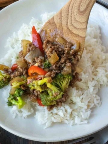 Spooning ground beef and broccoli over rice.