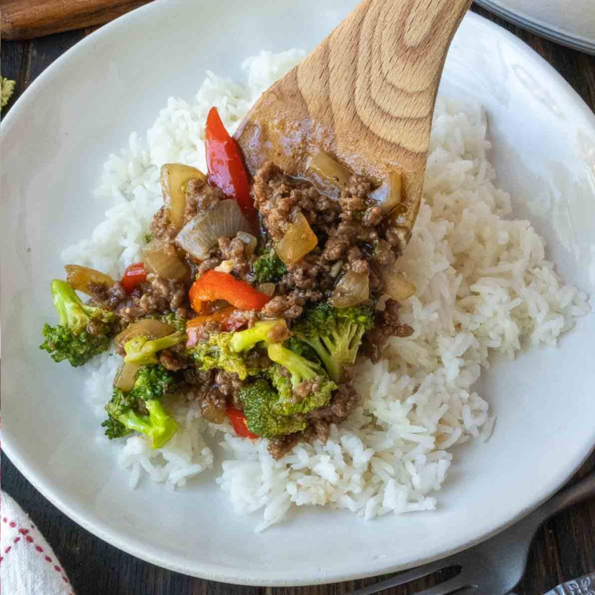 Spooning ground beef and broccoli over rice.