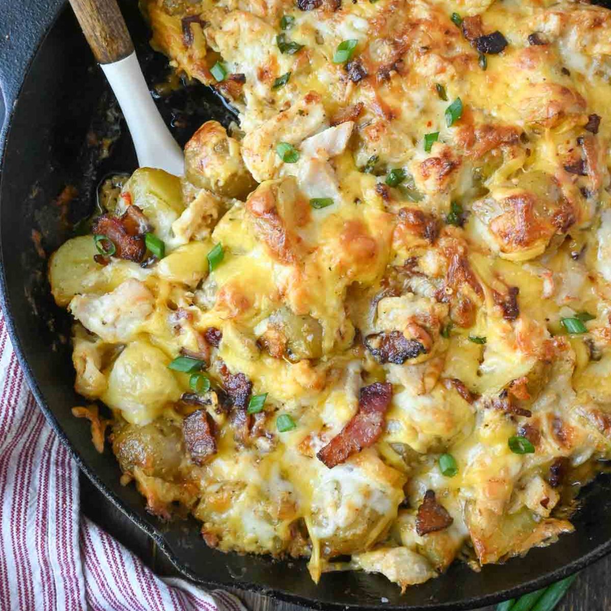 Cheesy potato casserole with a spatula in it.