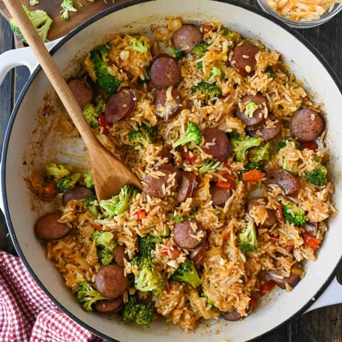 A wooden spoon in a skillet with sausage rice.