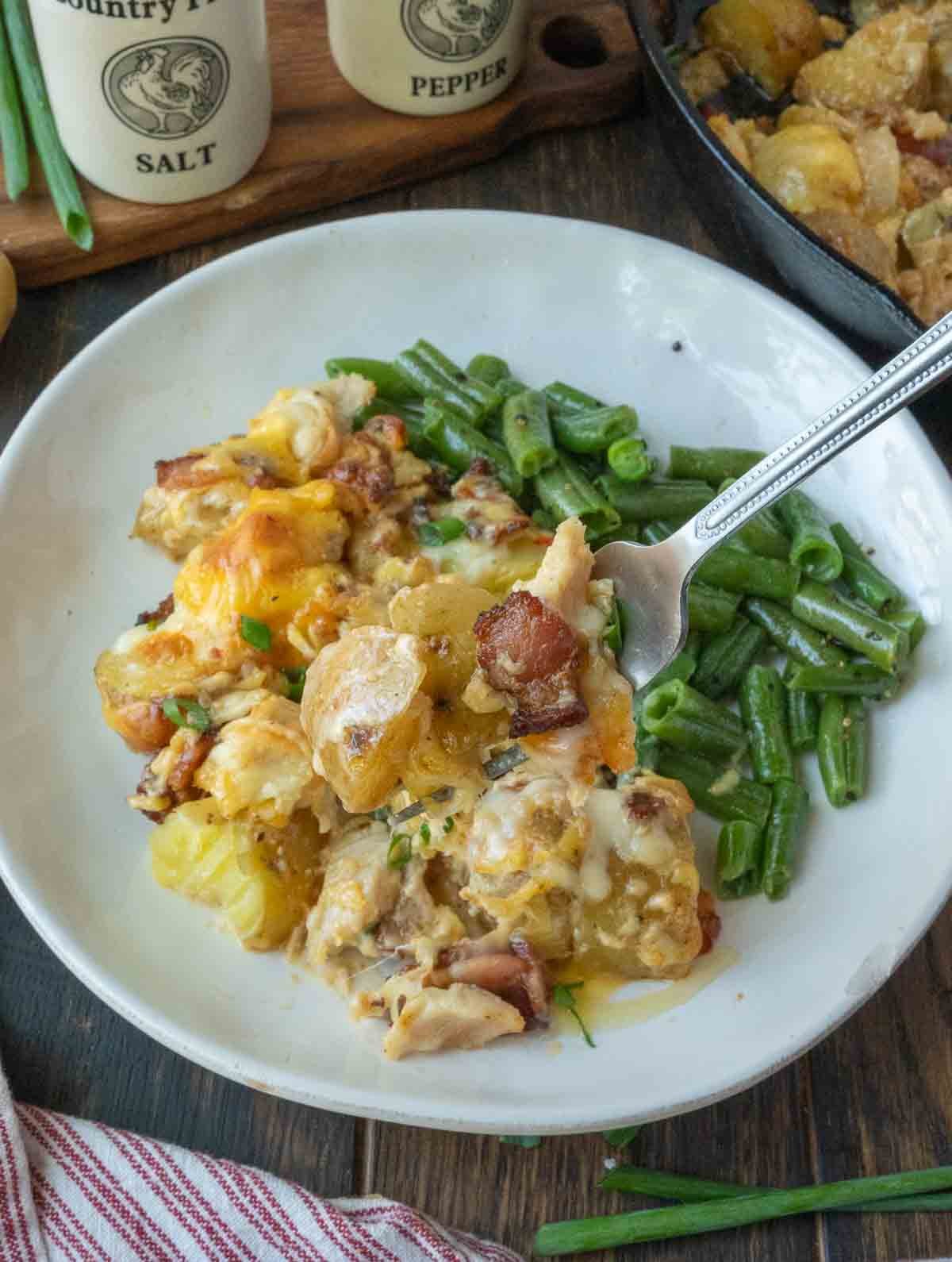Potato casserole on a plate with green beans.