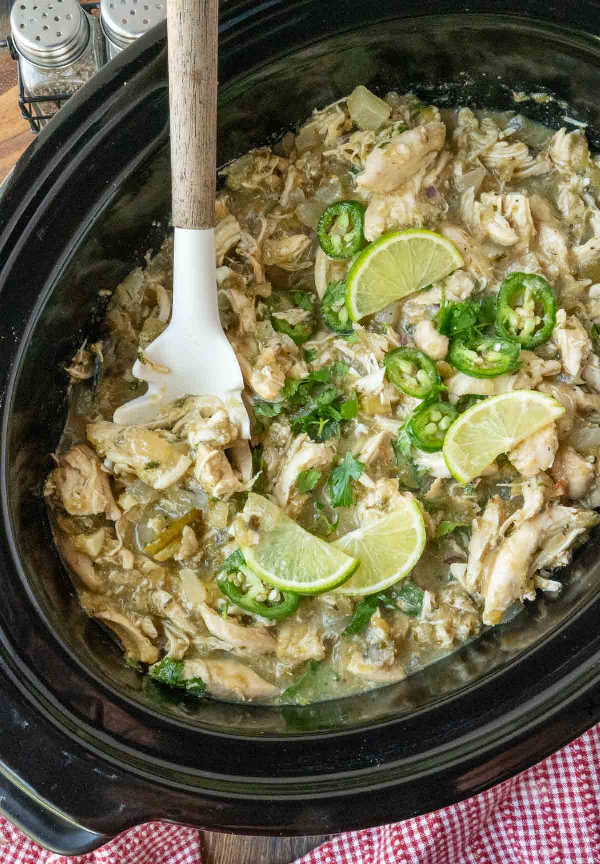 Stirring salsa verde chicken in a slow cooker.