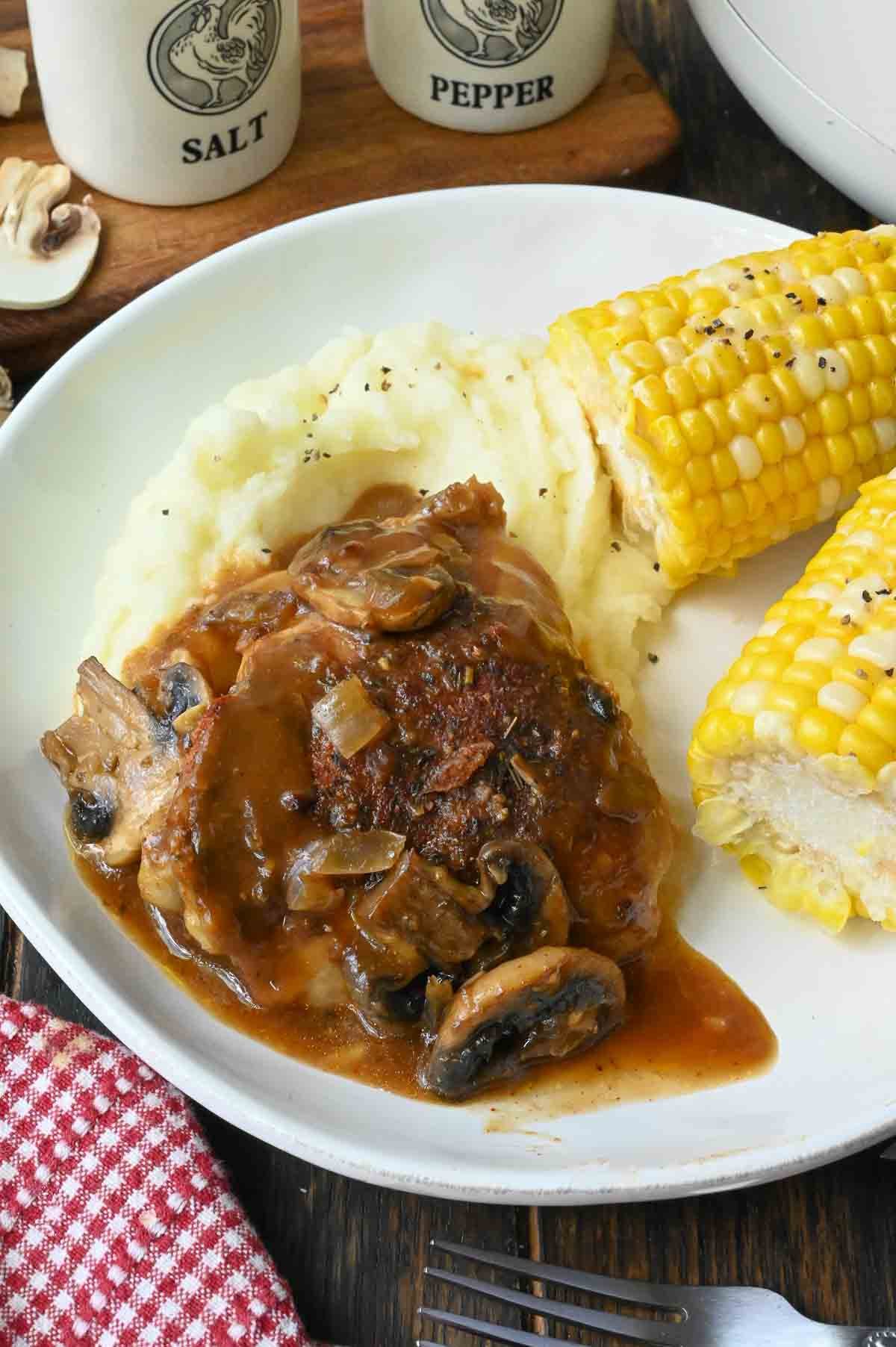 A plate of slow cooker smothered chicken with mashed potatoes and corn.