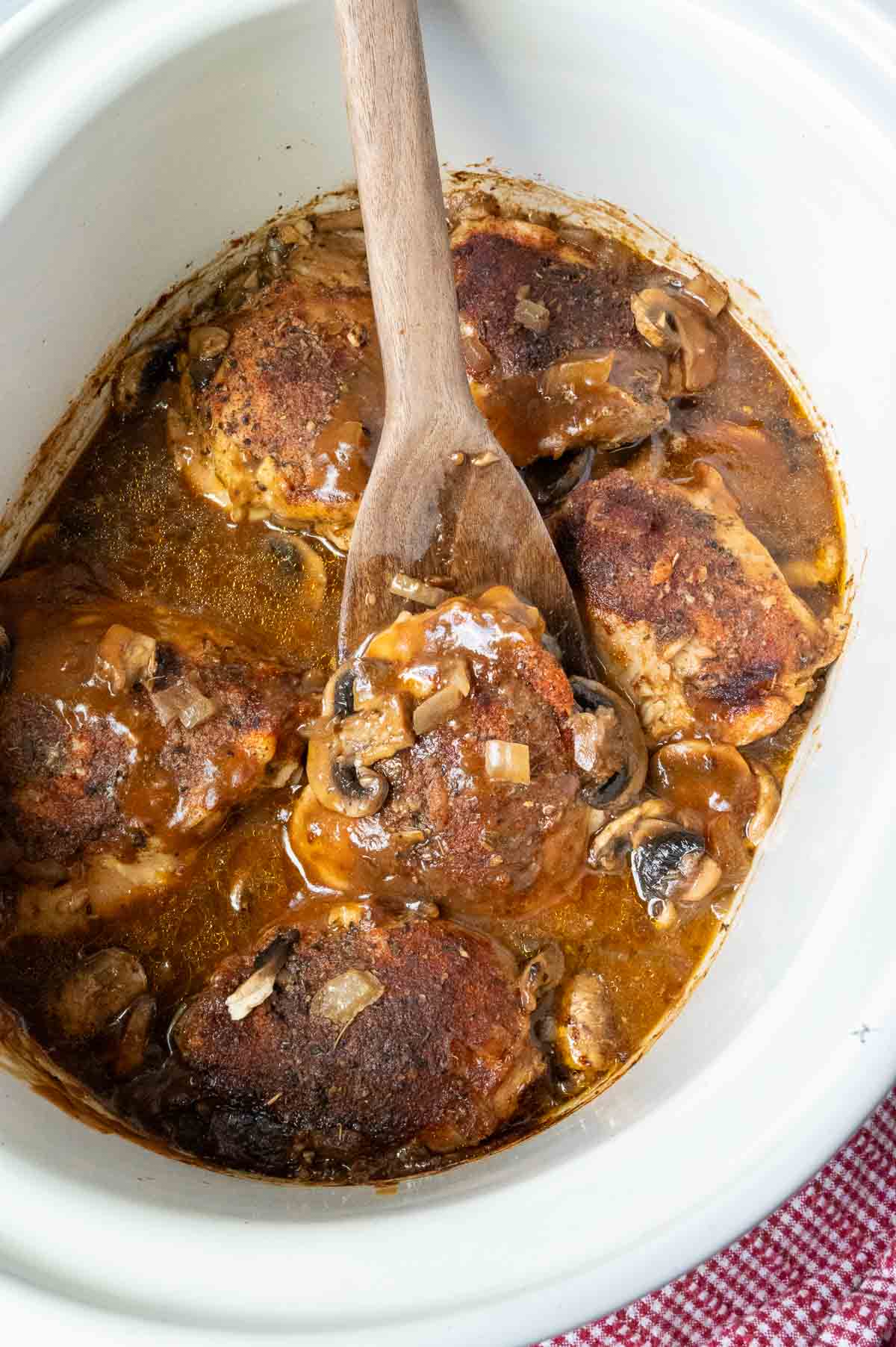 Stirring slow cooker smothered chicken in the crock pit.
