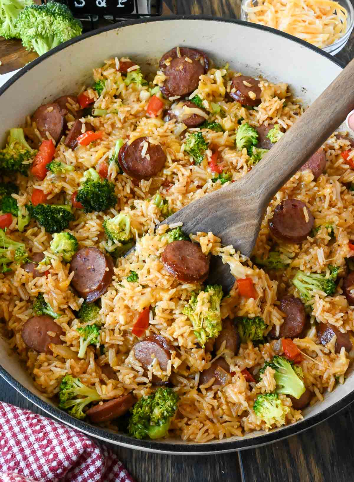 A wooden spatula scooping up some sausage rice.
