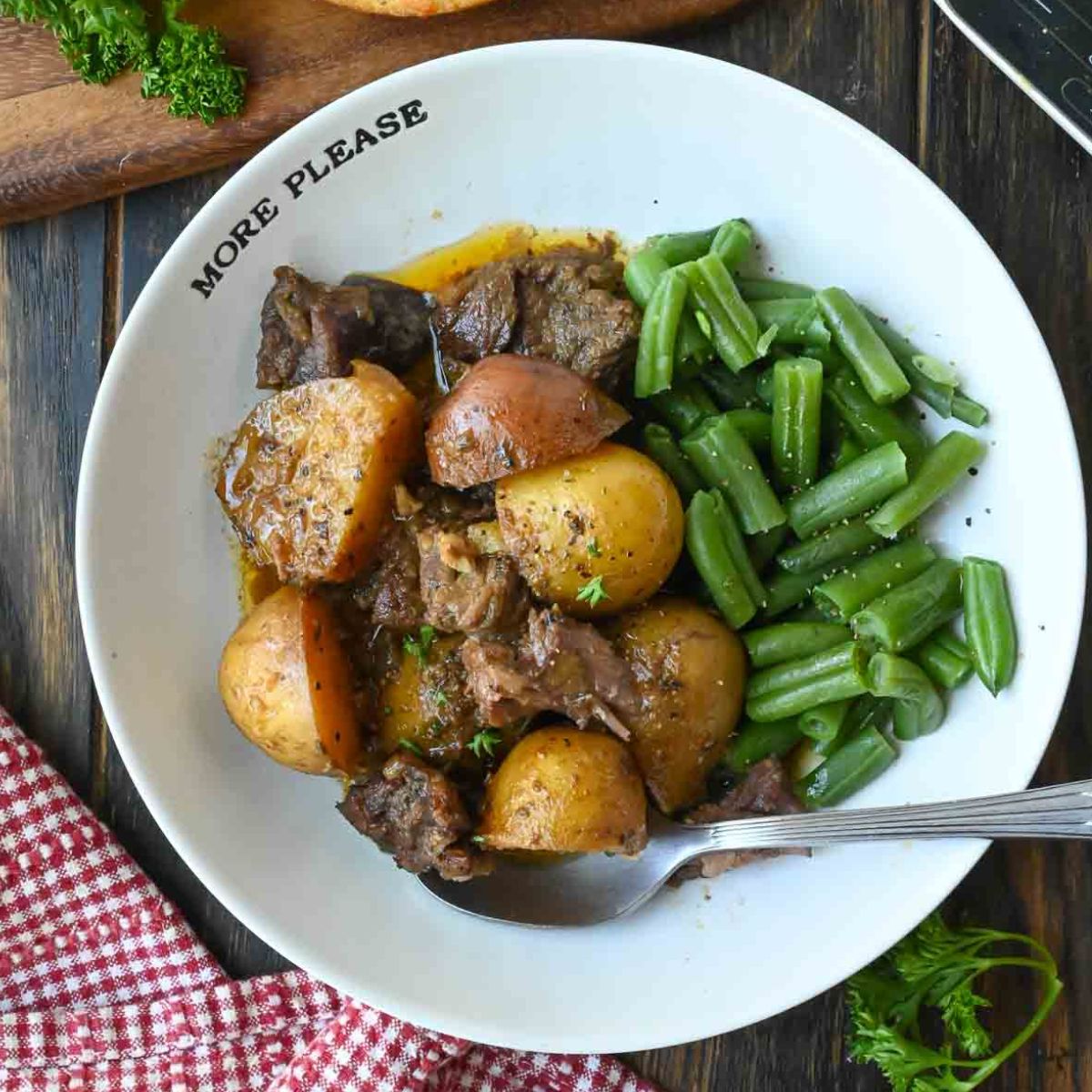 A bowl of steak and potatoes with green beans.