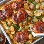A sheet pan with baked chicken potatoes and green beans.