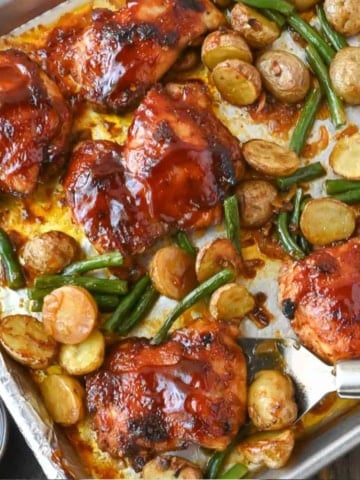 A sheet pan with baked chicken potatoes and green beans.
