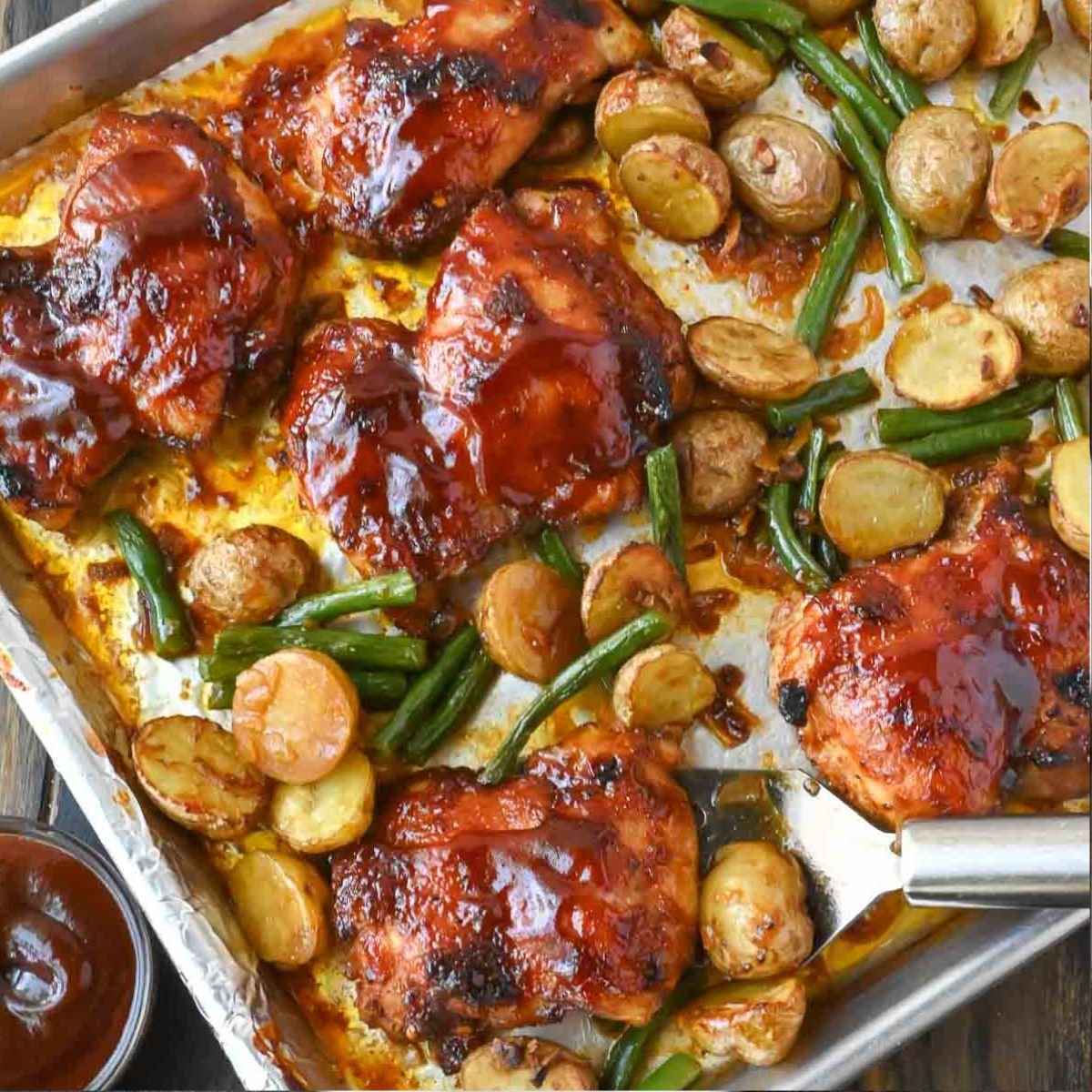A sheet pan with baked chicken potatoes and green beans.
