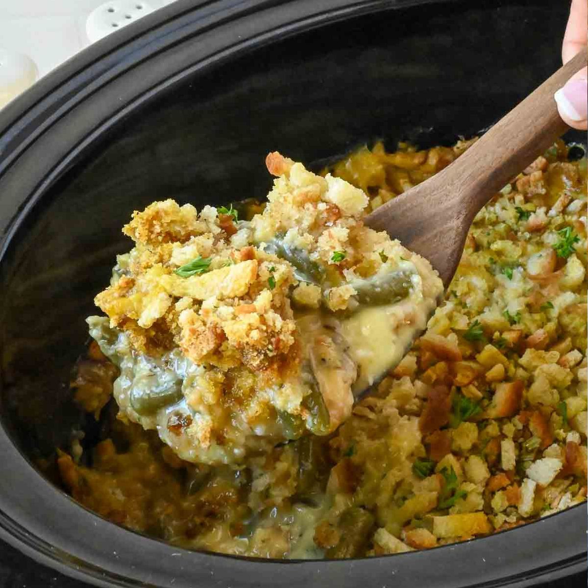 Slow cooker stuffing casserole being scooped up with a spoon.
