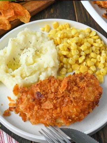 A plate of barbecue chip chicken tenders with corn and mashed potatoes.