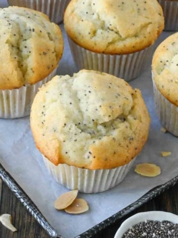 Close up of almond poppy seed muffins on a baking sheet.