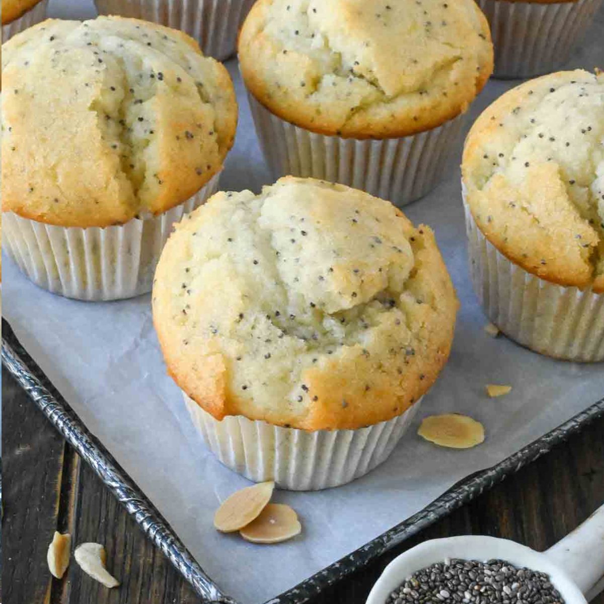 Close up of almond poppy seed muffins on a baking sheet.