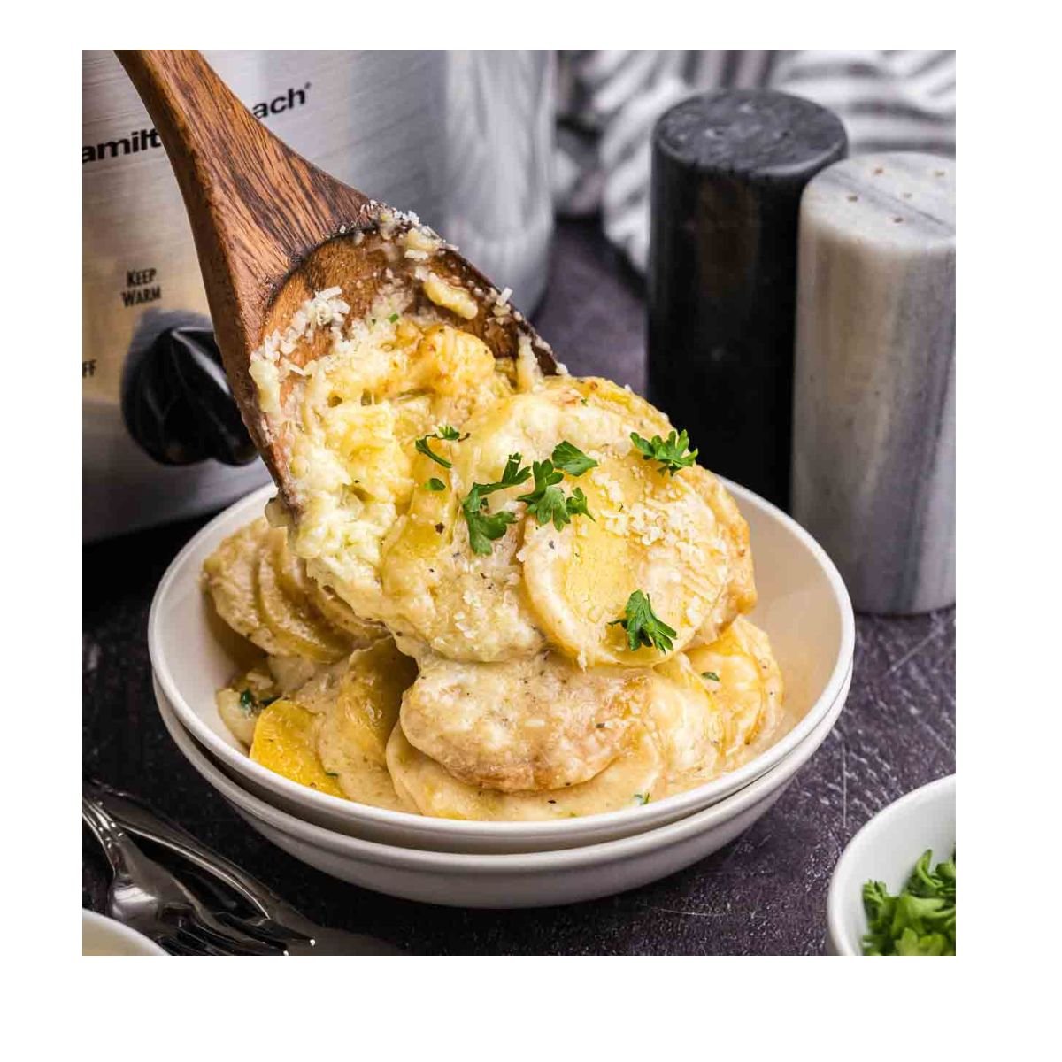 Spooning scalloped potatoes into a dish.