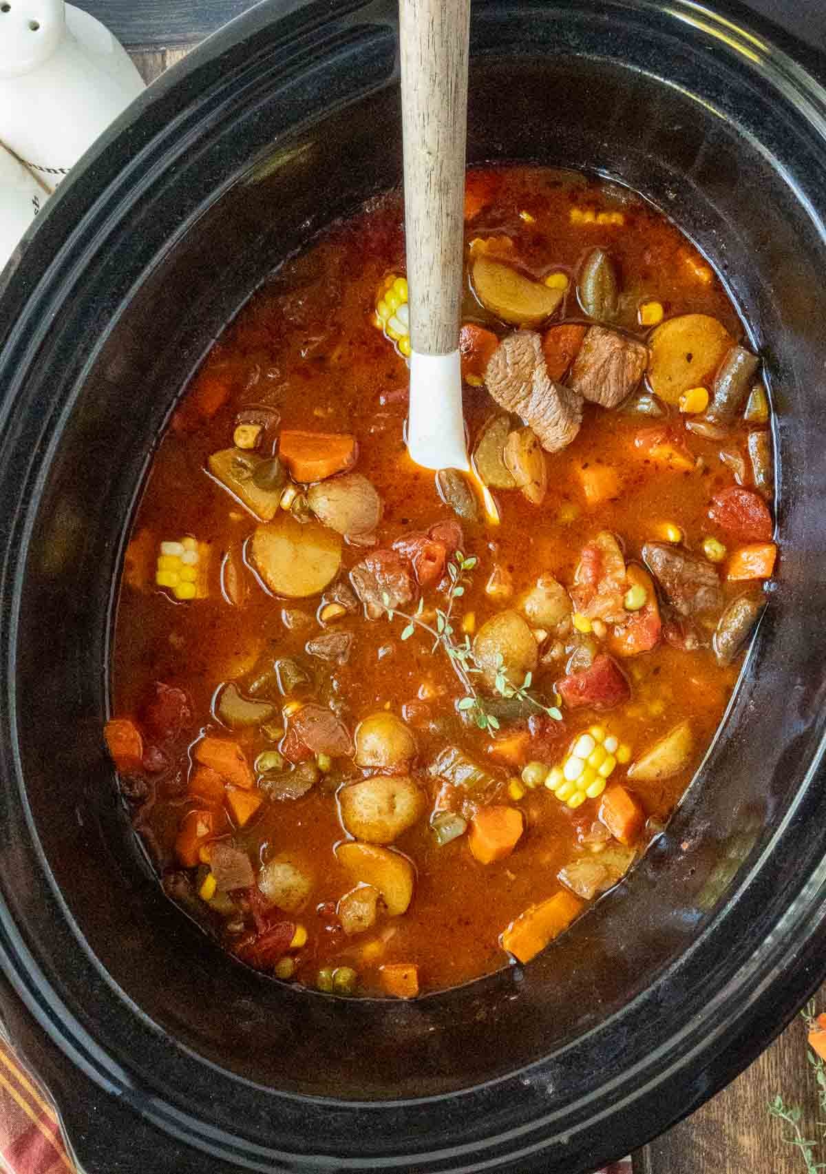 A wooden spoon in crockpot vegetable beef soup.