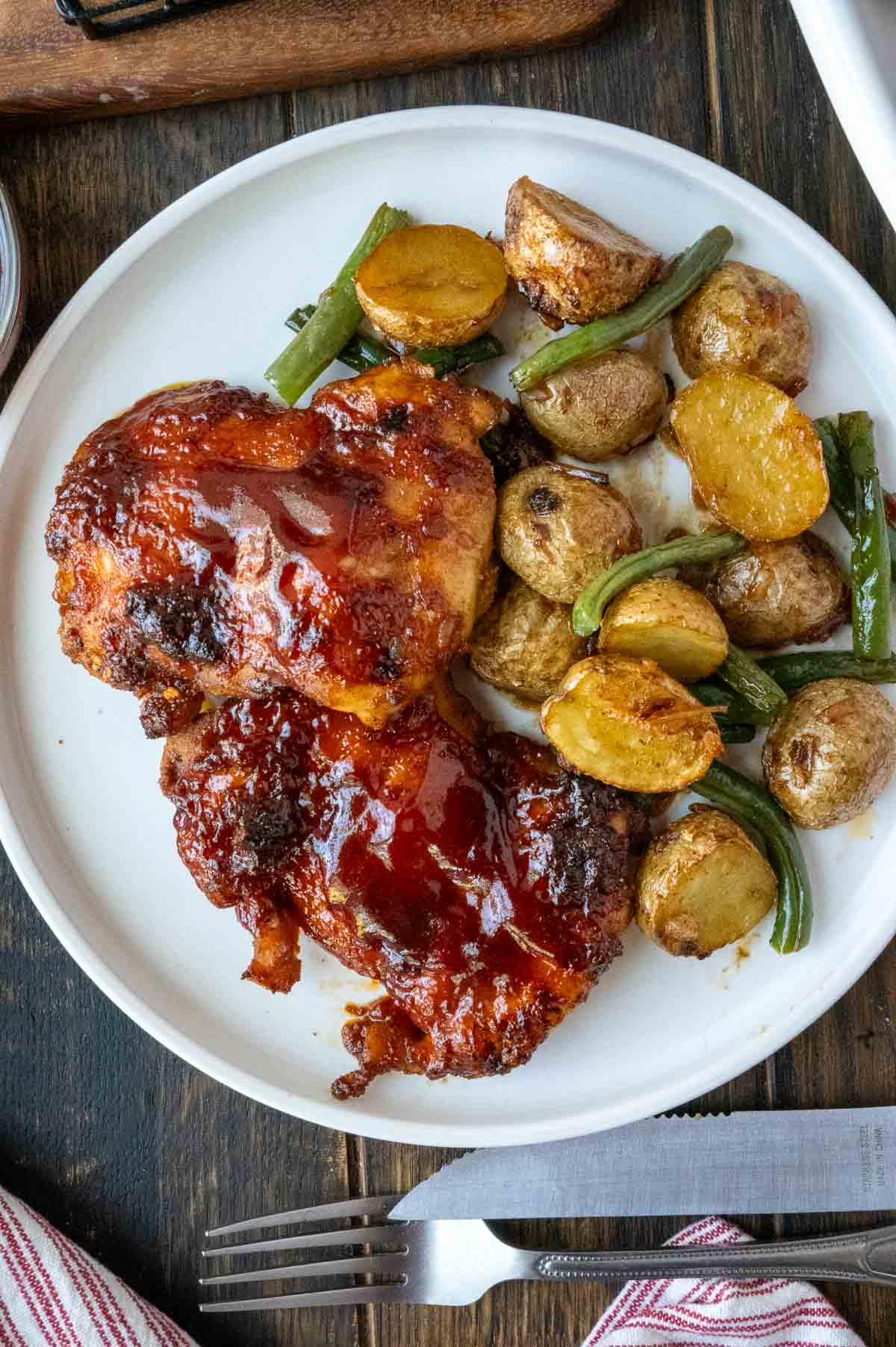 A plate with baked chicken potatoes and green beans.