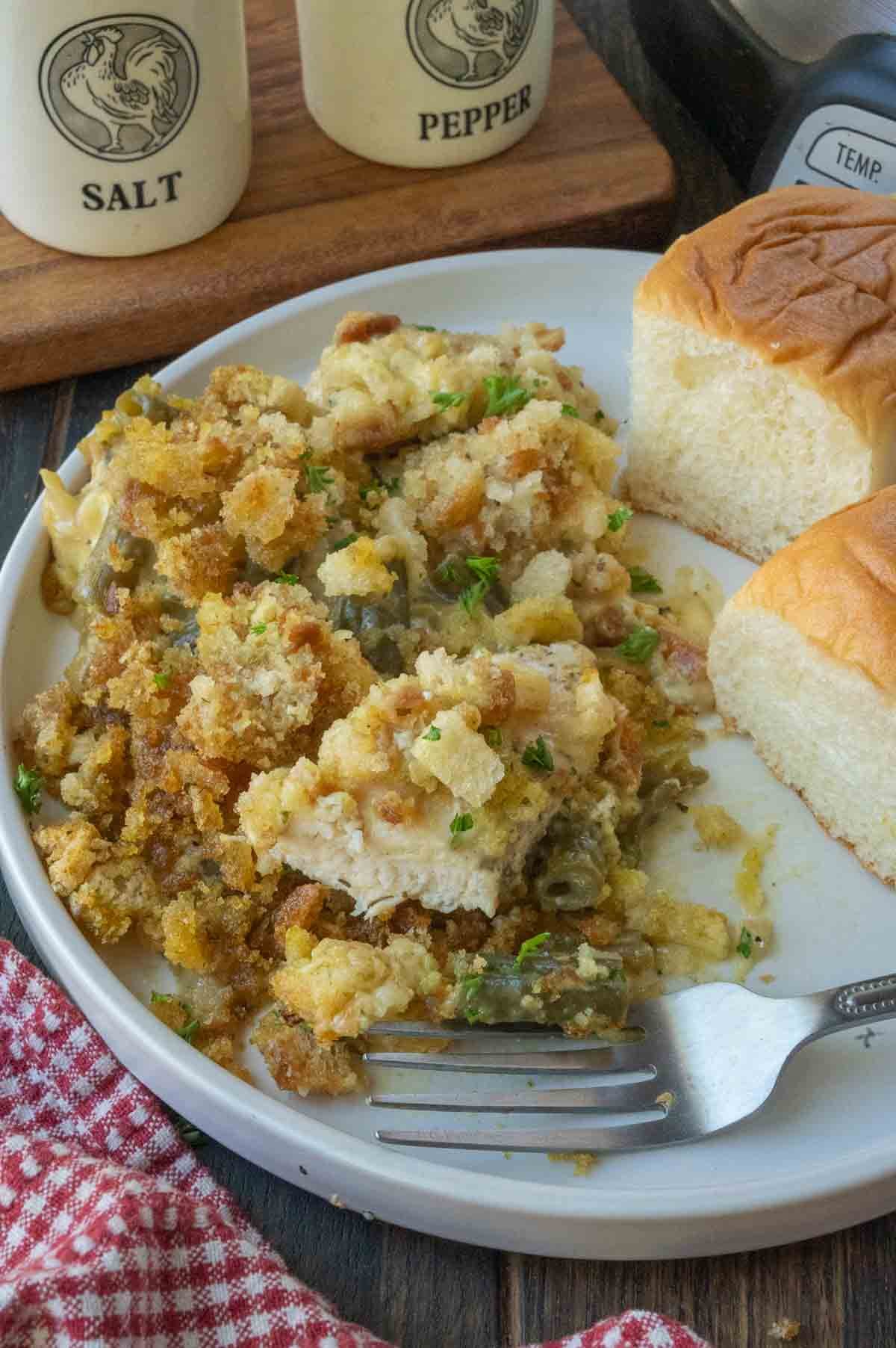 Stuffing casserole on a plate with dinner rolls.
