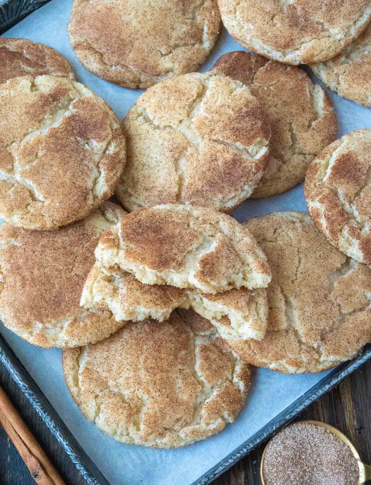 Snickerdoodles piled on a baking sheet.
