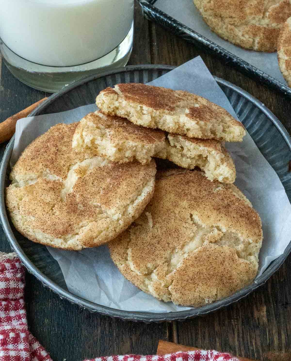 Chewy snickerdoodles on a plate with one broken in half.