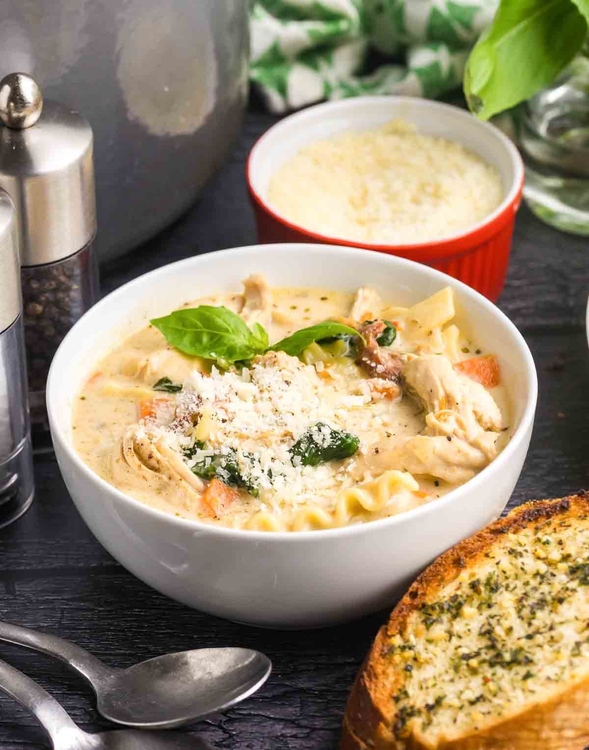 A bowl of white lasagna soup with a side of garlic bread.
