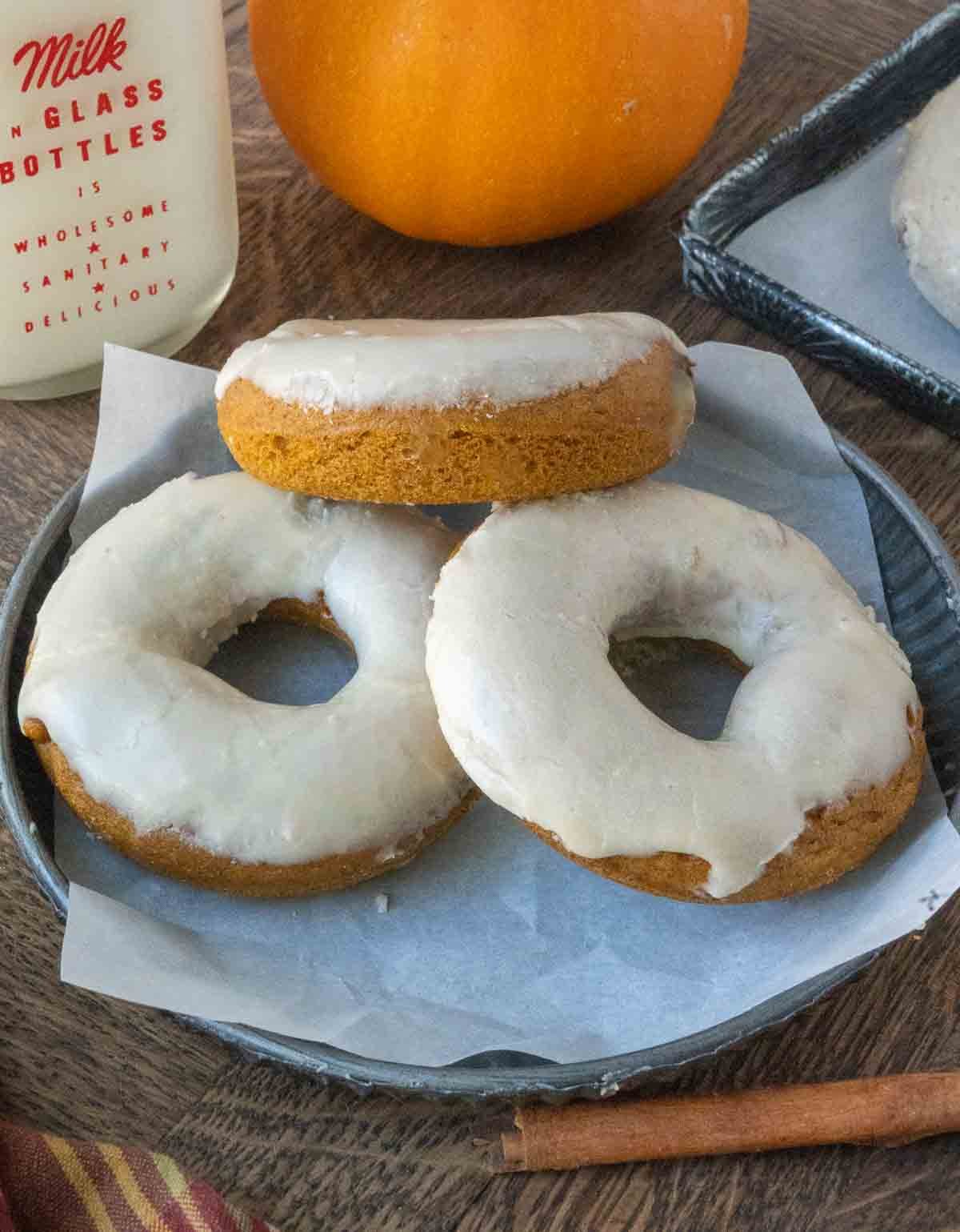 Three pumpkin donuts on a plate.