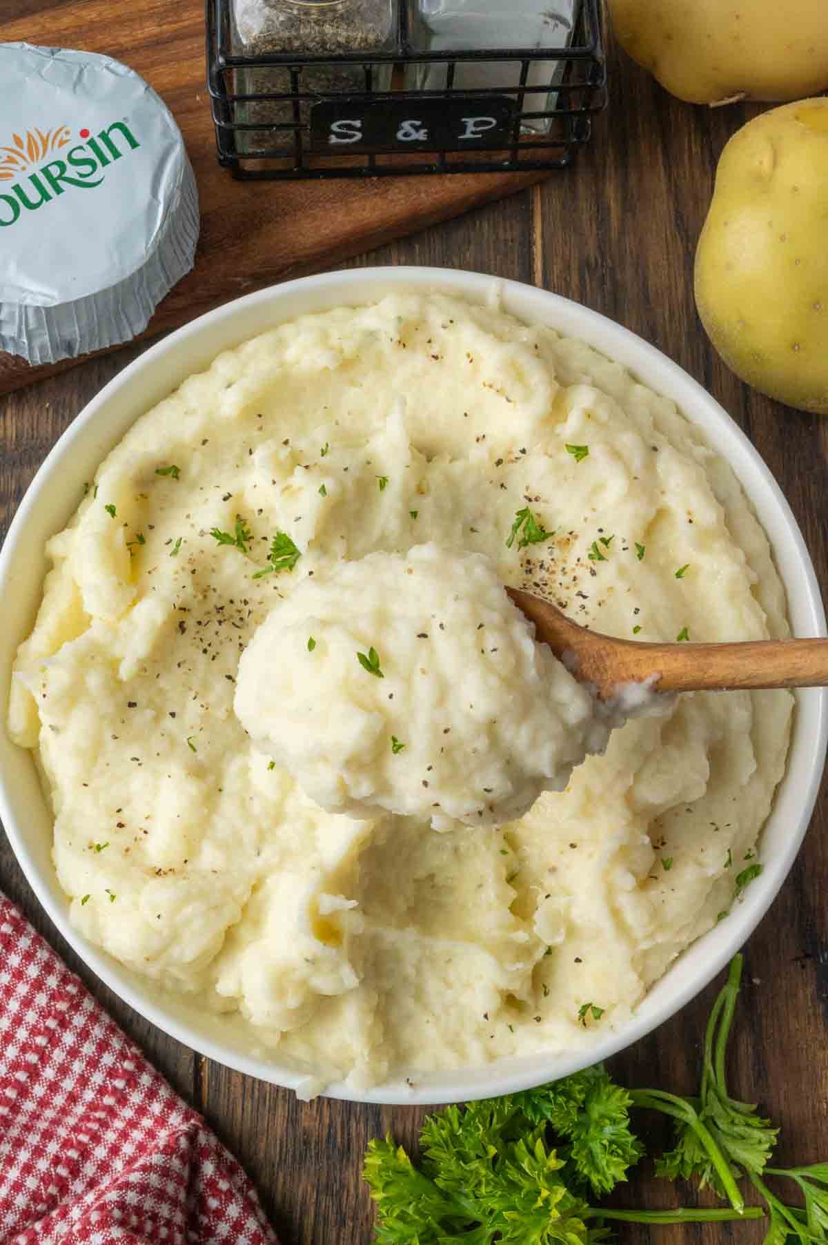 Taking a scoop of mashed potatoes from a white bowl.