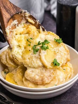Scalloped potatoes being served into a bowl.
