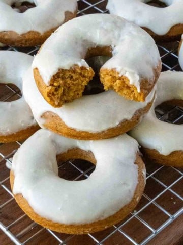 Baked pumpkin donuts on a cooling rack with maple icing.