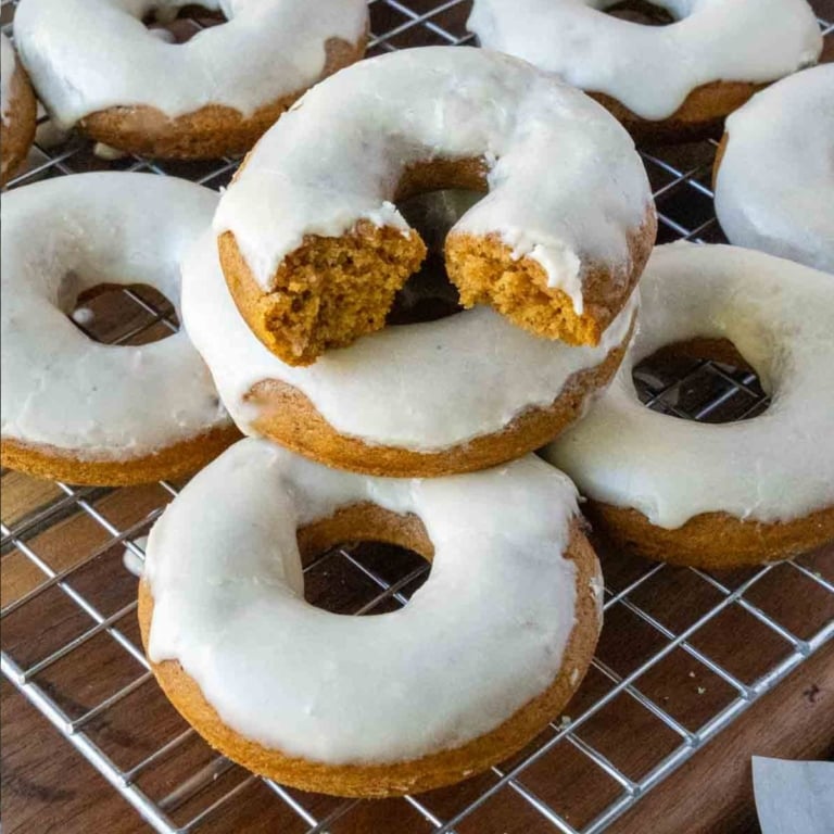 Baked pumpkin donuts on a cooling rack with maple icing.