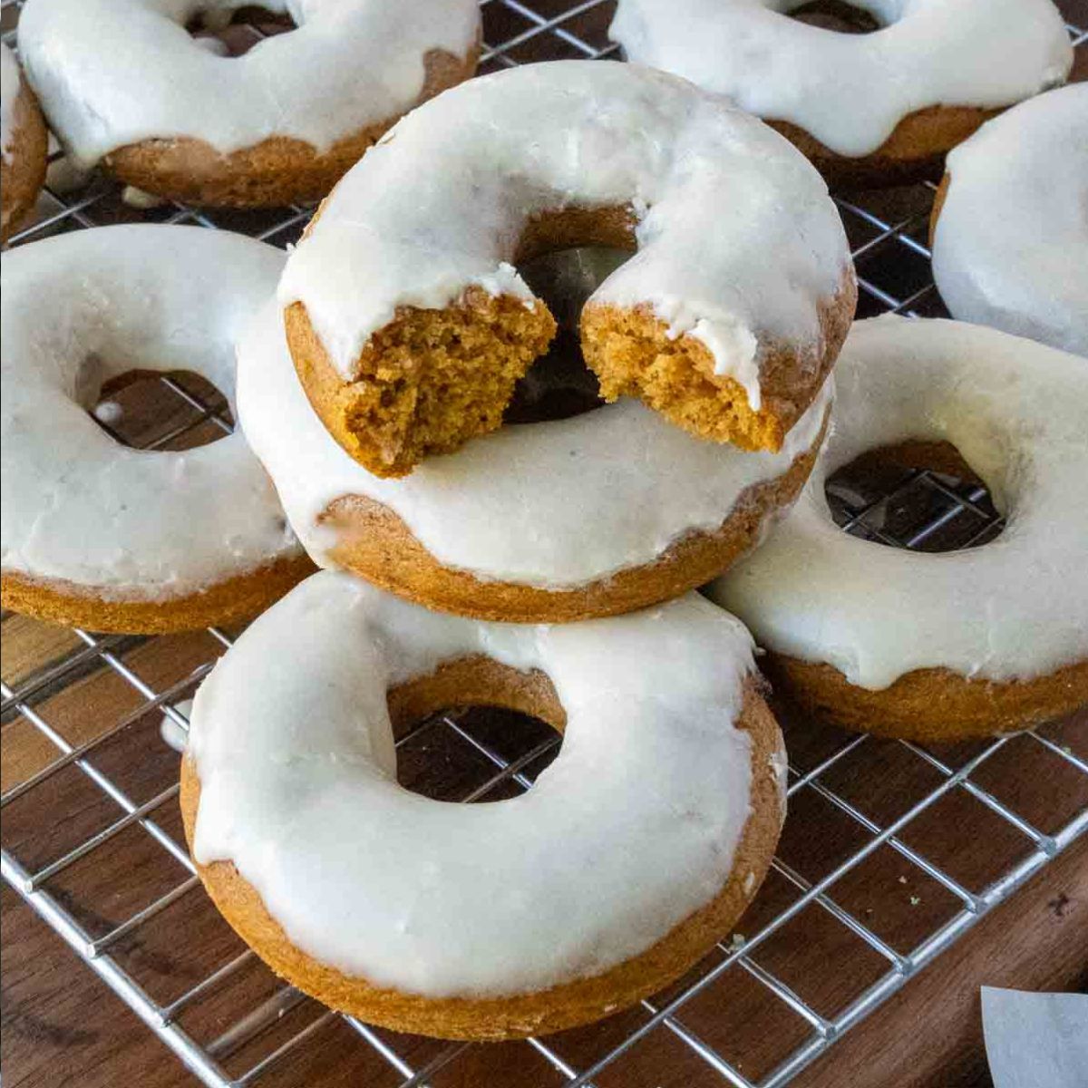Baked pumpkin donuts on a cooling rack with maple icing.
