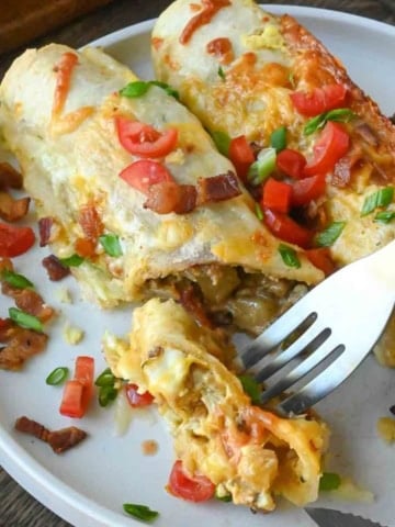 A fork taking a bite out of a breakfast enchilada.