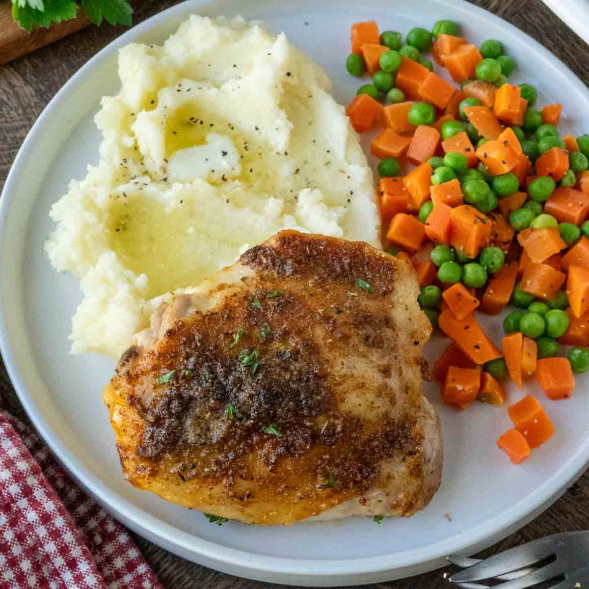 A plate of crispy roasted chicken with mashed potatoes and vegetables.