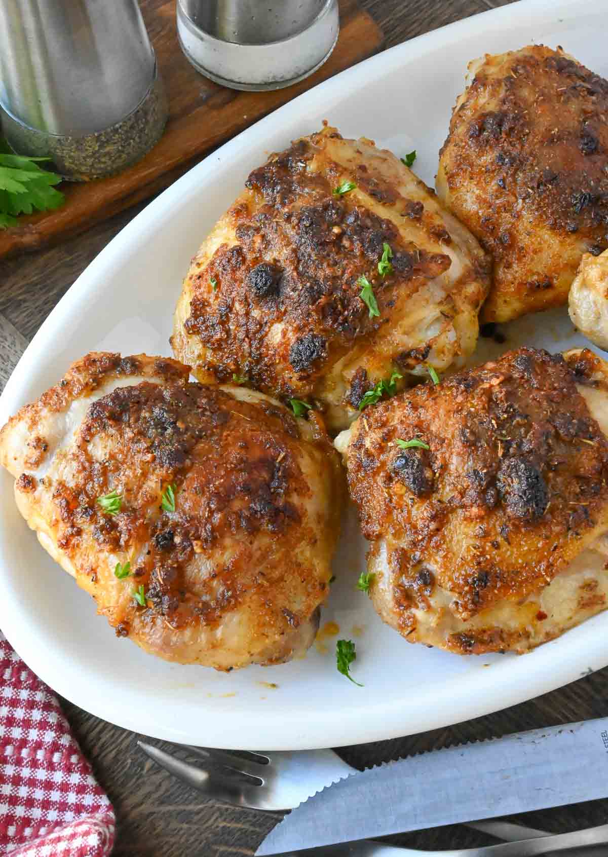 Roasted chicken thighs on a white serving platter.