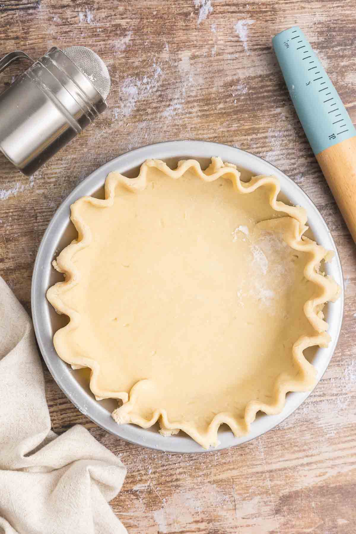Homemade pie crust with crimped edges in a silver pie tin.