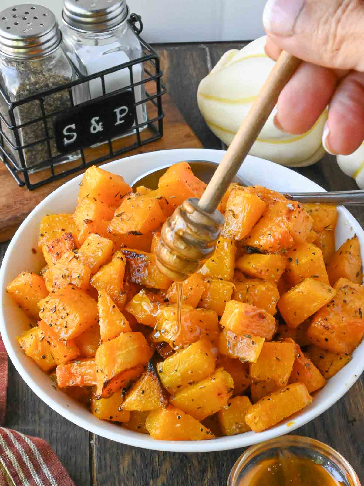 Honey being drizzled over the top of roasted butternut squash.