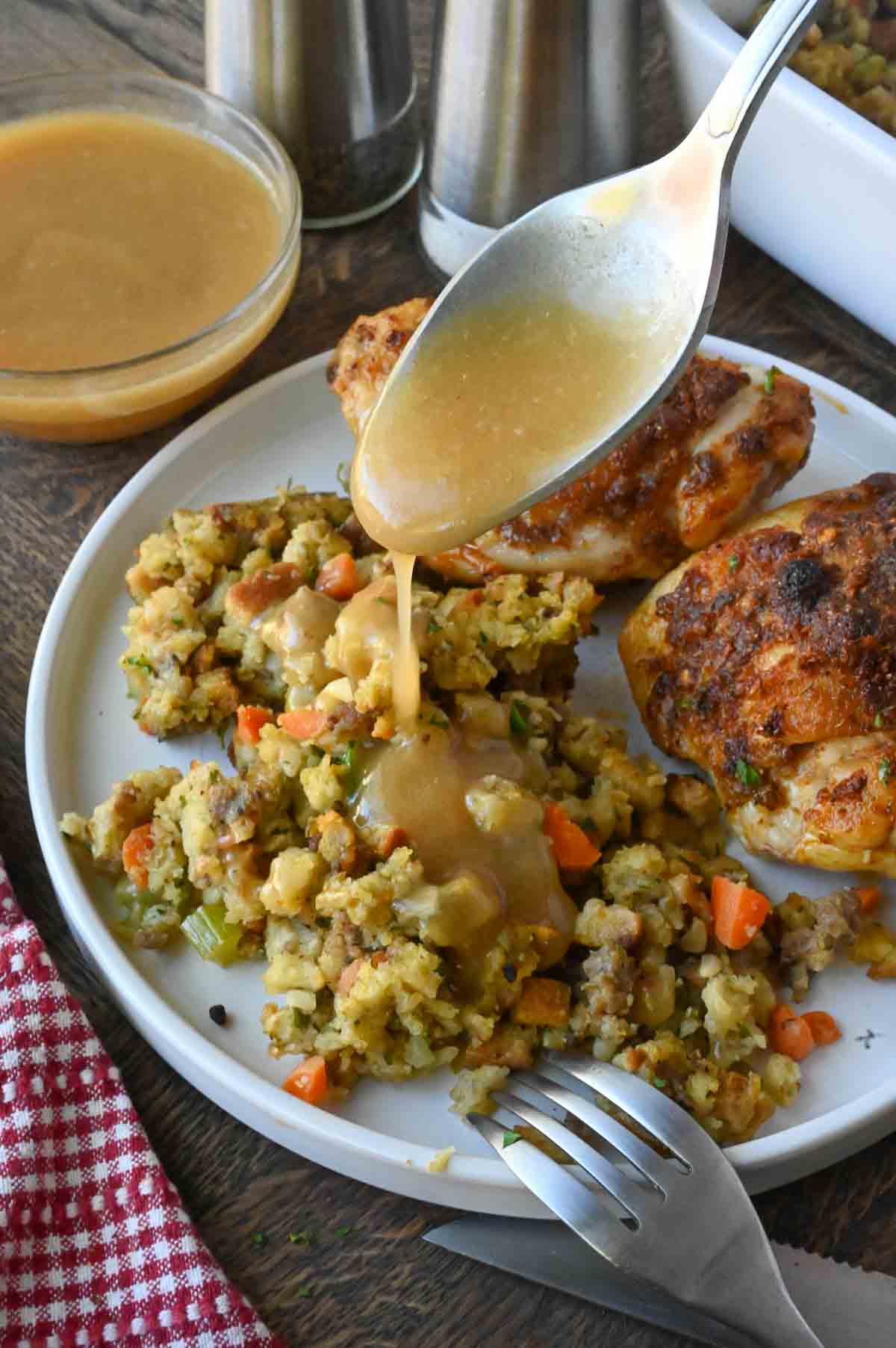 Drizzling gravy over a plate of stuffing.