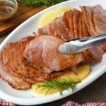 A ham slice being picked up with tongs.