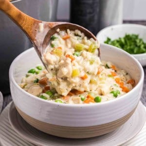 Stirring a bowl of creamy chicken and rice soup.