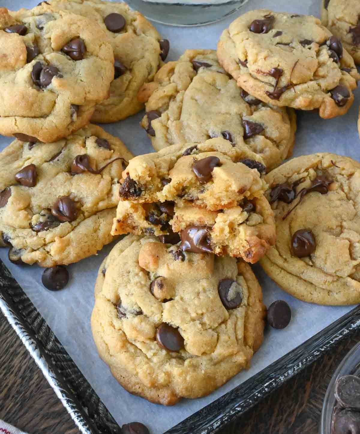 Chocolate chip cookies on a baking sheet with one broken in half.