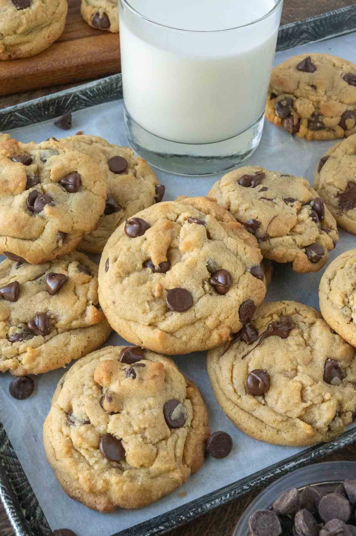 Cookies on a baking sheet with a glass of milk.