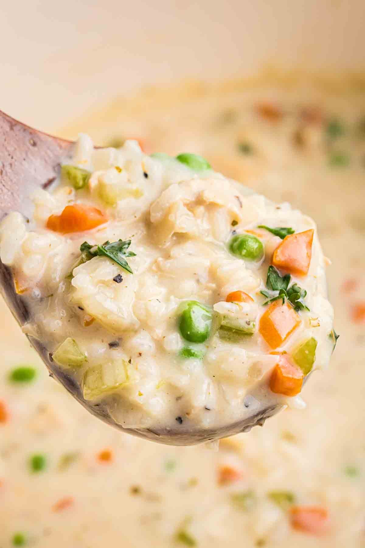 Close up view of a large spoonful of chicken and rice soup.