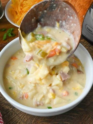 A ladle pouring soup into a bowl.
