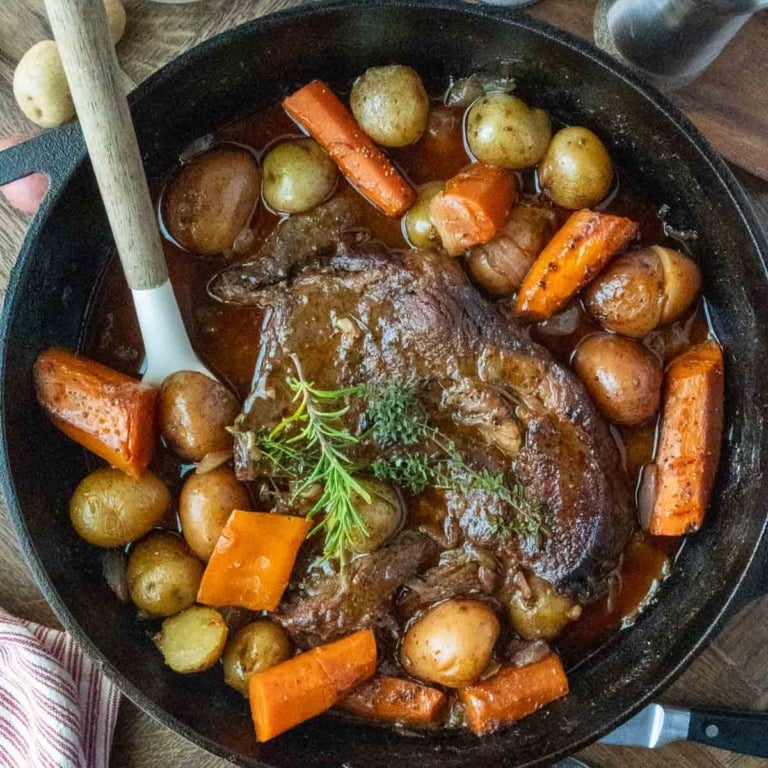 Pot roast in a pot with baby potatoes and carrots.