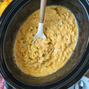Mac and cheese in a slow cooker with a serving spoon.