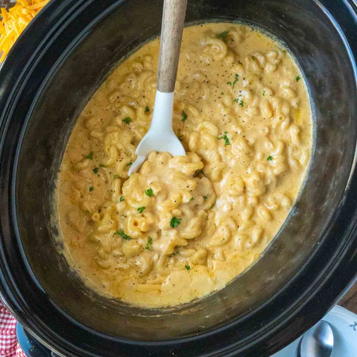 Mac and cheese in a slow cooker with a serving spoon.