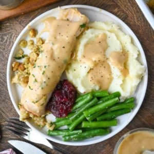 A plate of turkey stuffing roll up with green beans and mashed potatoes.